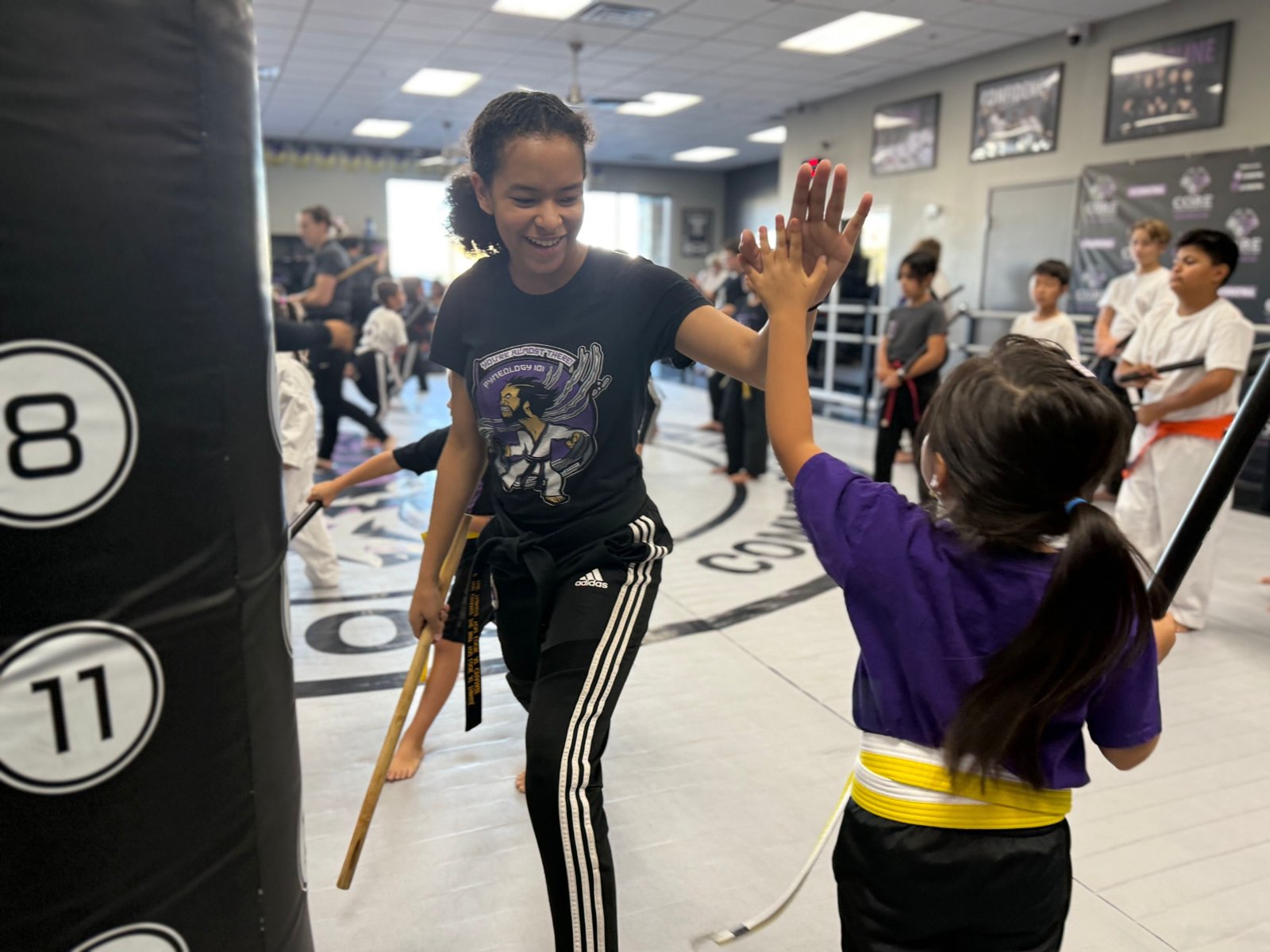 A coach high-fiving a young student at CORE Fitness & Martial Arts in Henderson
