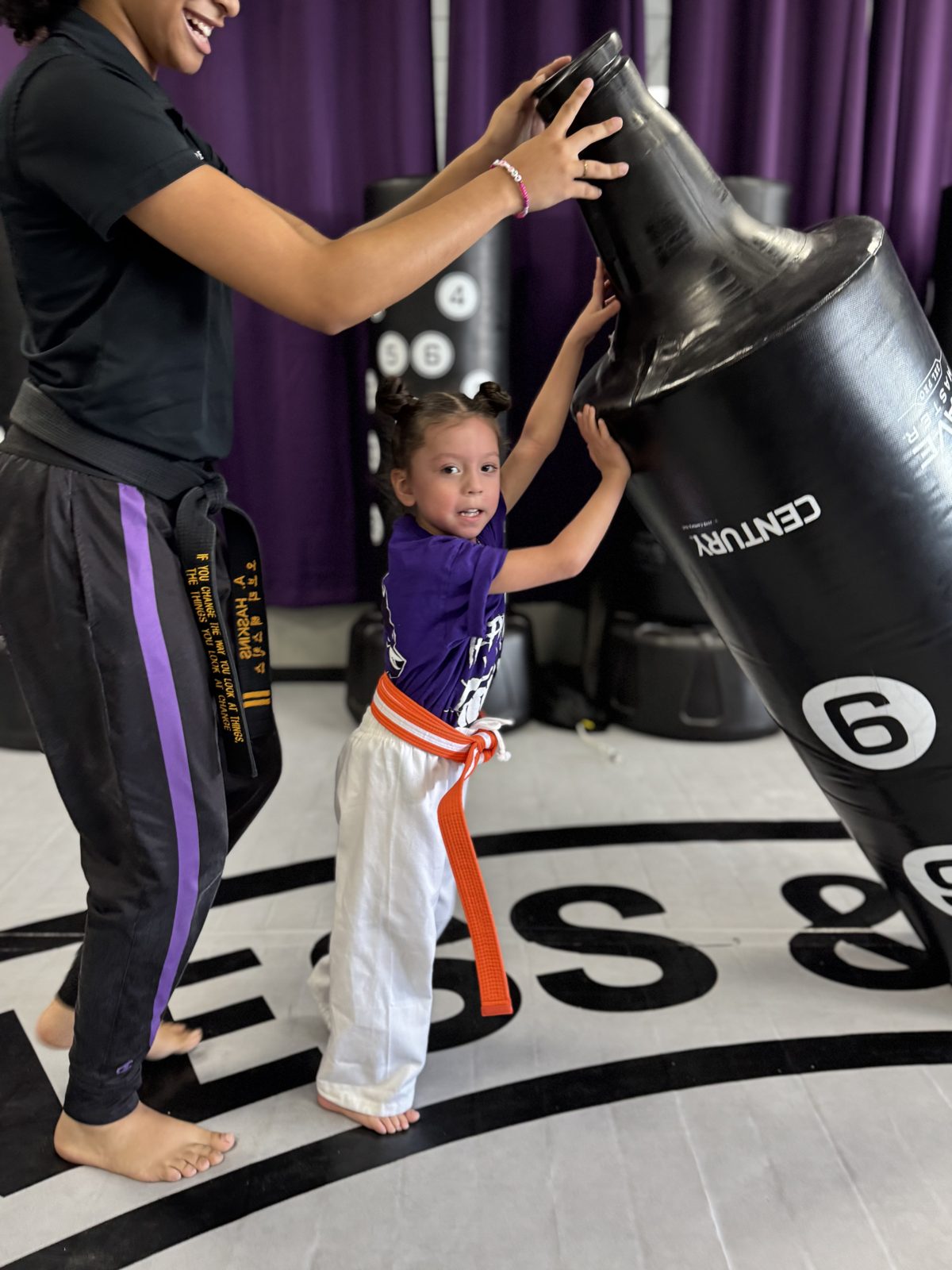 A Wolf Pup pushing a heavy bag with help from a coach at CORE Fitness & Martial Arts in Henderson