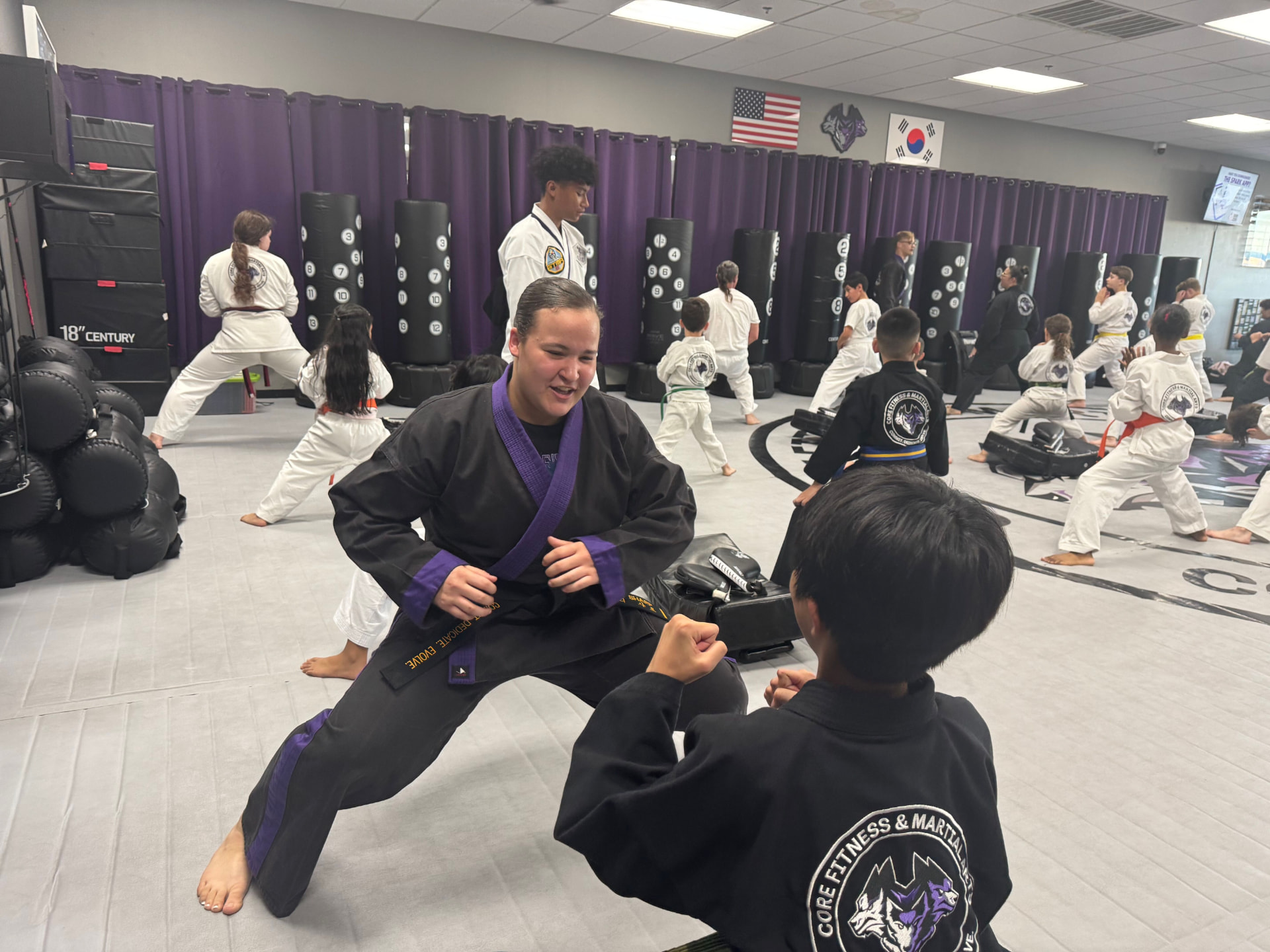 A smiling instructor in a purple-trimmed uniform squaring off with a student during class at CORE Fitness & Martial Arts in Henderson