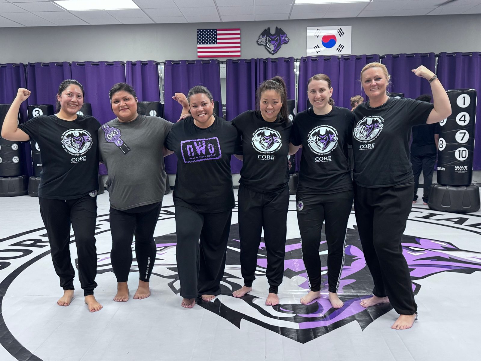 Women Warrior students in black CORE shirts flexing together at CORE Fitness & Martial Arts in Henderson