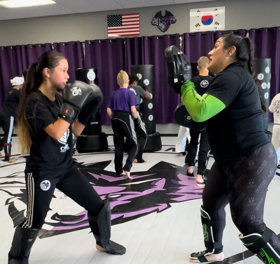 An adult student striking pads held by a coach at CORE Fitness & Martial Arts in Henderson