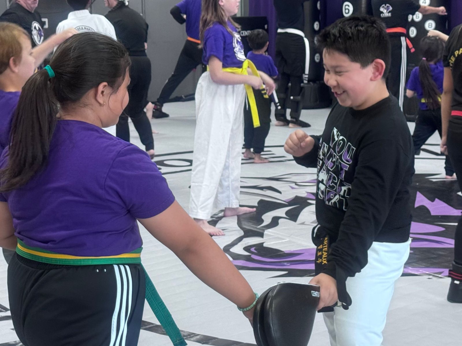 A Family Program student kicking a pad held by a partner at CORE Fitness & Martial Arts in Henderson