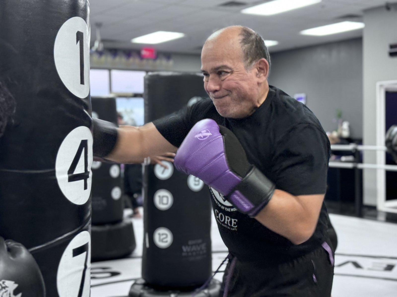 A Warrior student in boxing gloves hitting the heavy bag at CORE Fitness & Martial Arts in Henderson
