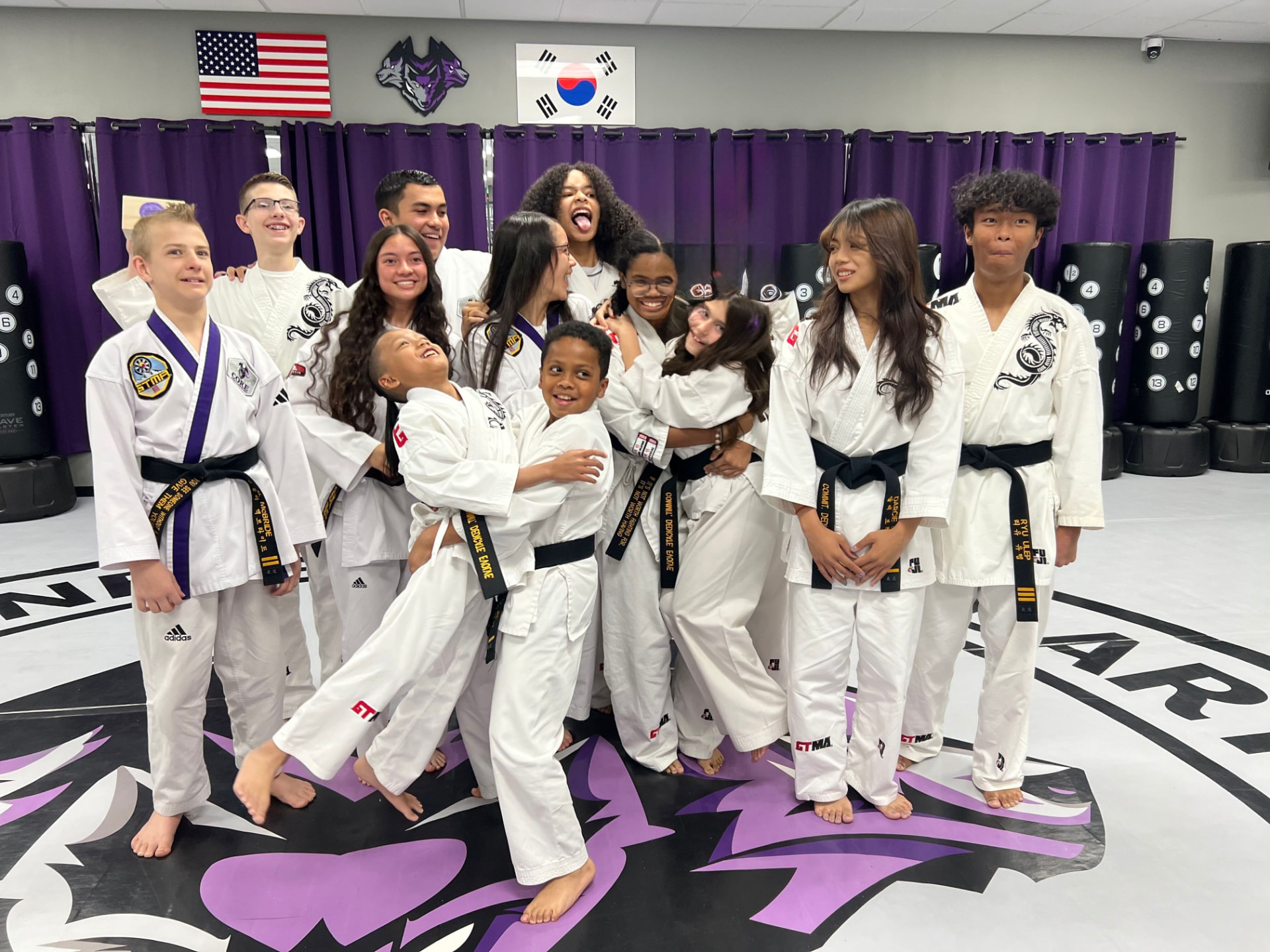 Young black belts laughing and hugging on the wolf logo mat at CORE Fitness & Martial Arts in Henderson