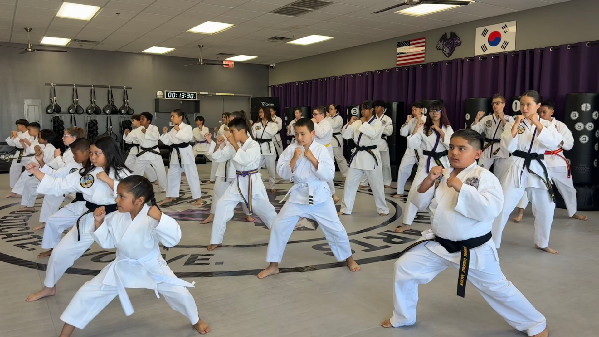 Kids and teens in white uniforms holding a fighting stance during class at CORE Fitness & Martial Arts in Henderson
