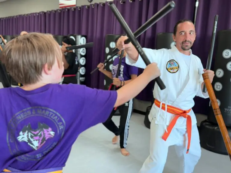 Martial arts instructor teaching self-defense stick technique to student during class